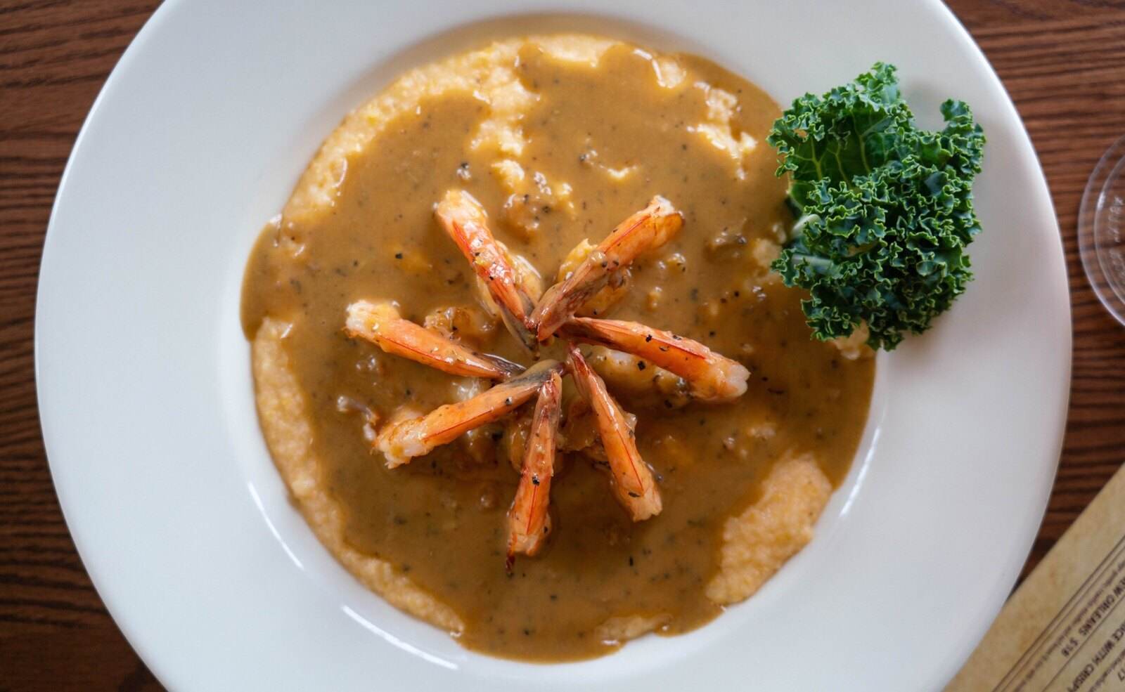 BBQ shrimp and grits: tail-on Gulf shrimp in New Orleans-style lemon butter and pepper sauce over corn grits at Mambo's