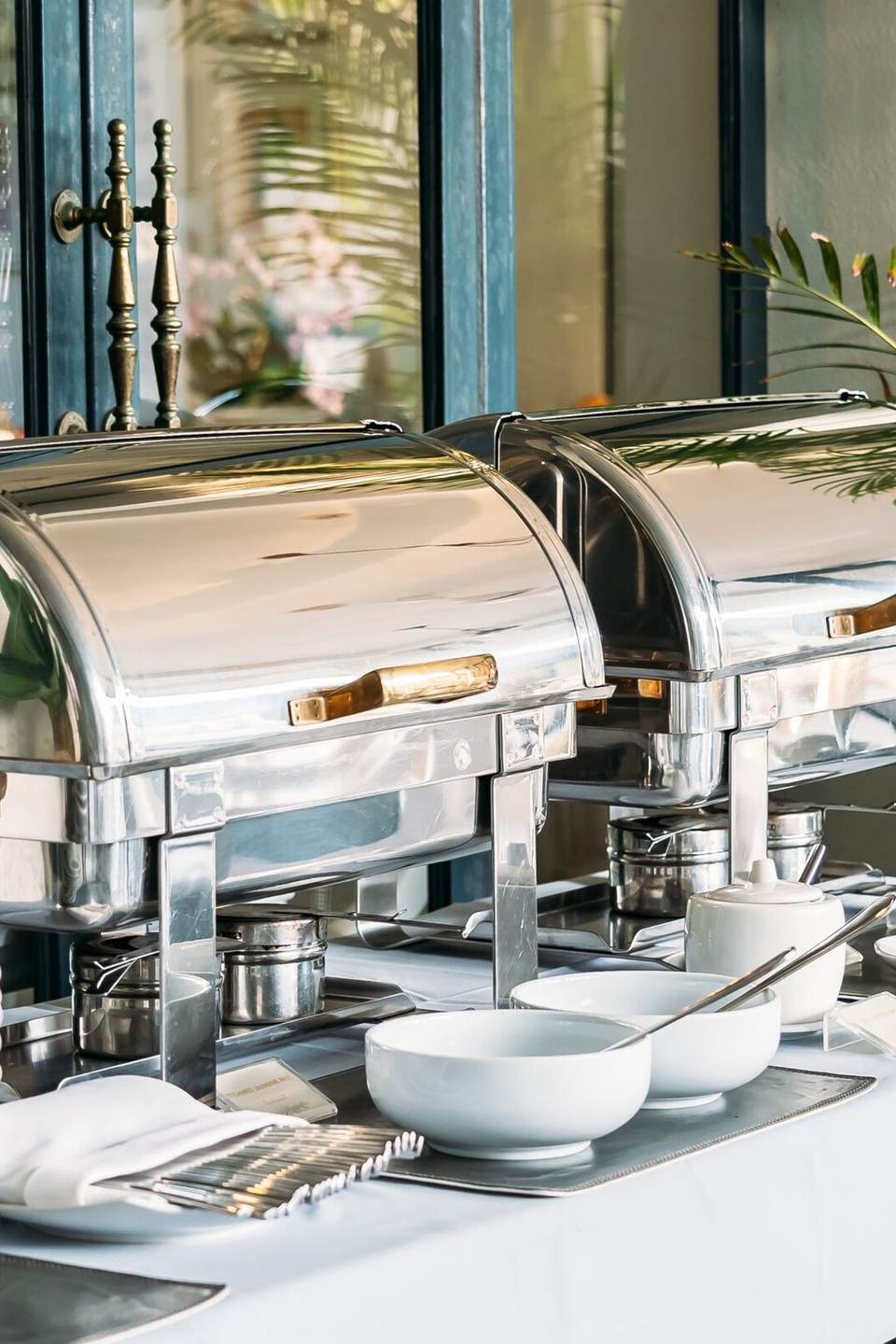 Catering buffet set-up with polished chafing dishes and stacked plates