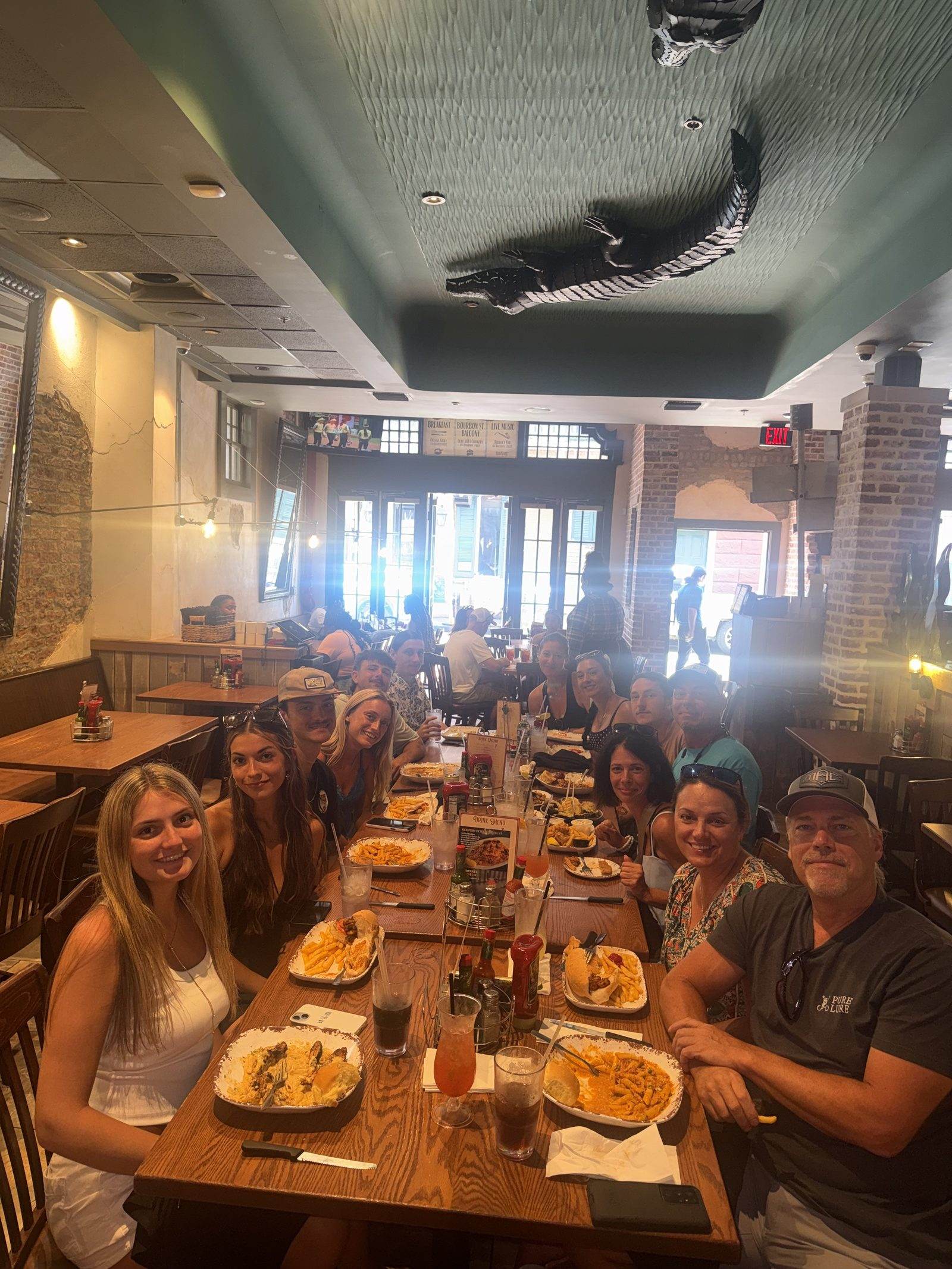 A long table of friends sharing a meal in Mambo's main dining room, under the alligator ceiling