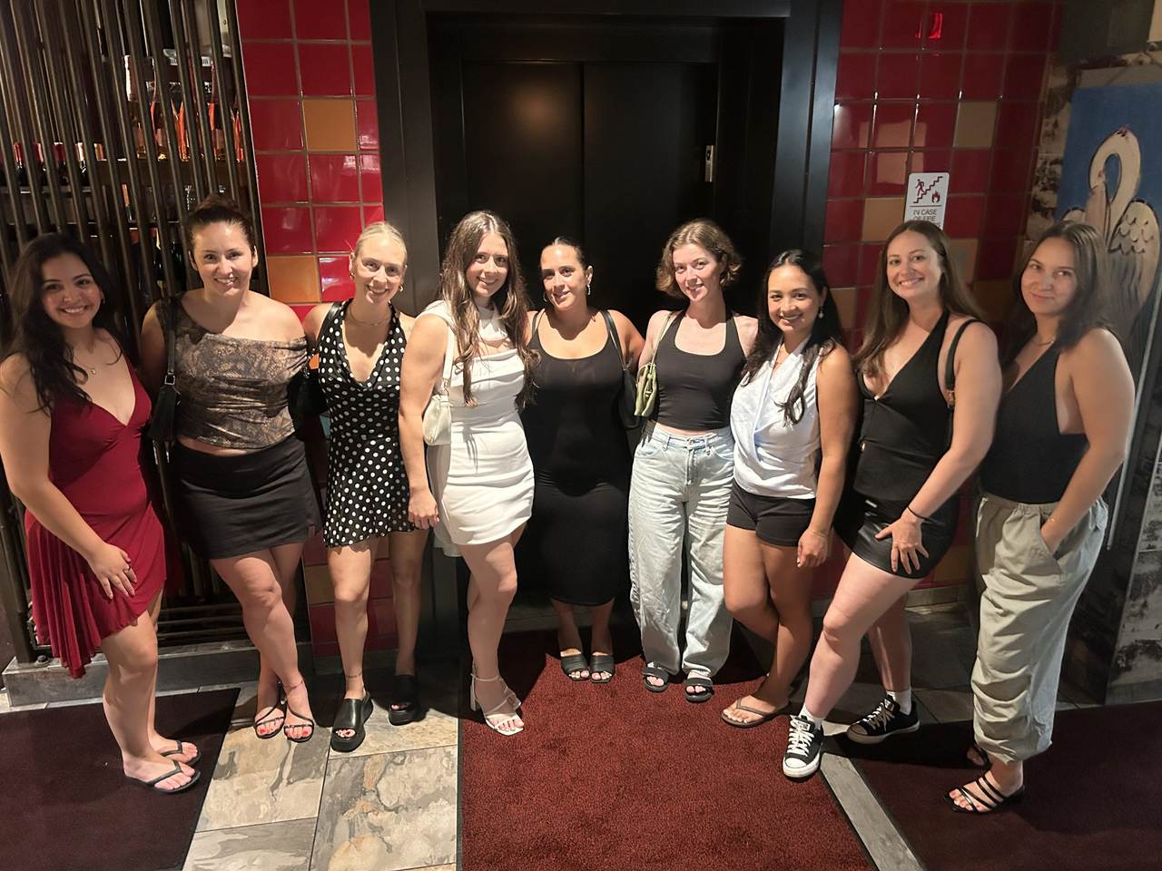 Nine friends dressed up for a night out, lined up together inside Mambo's