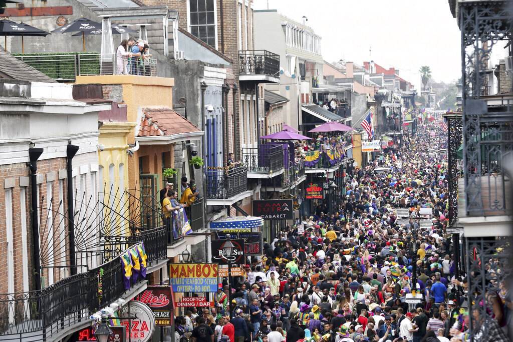 Mardi Gras crowds packing Bourbon Street below balconies and Mambo's sign