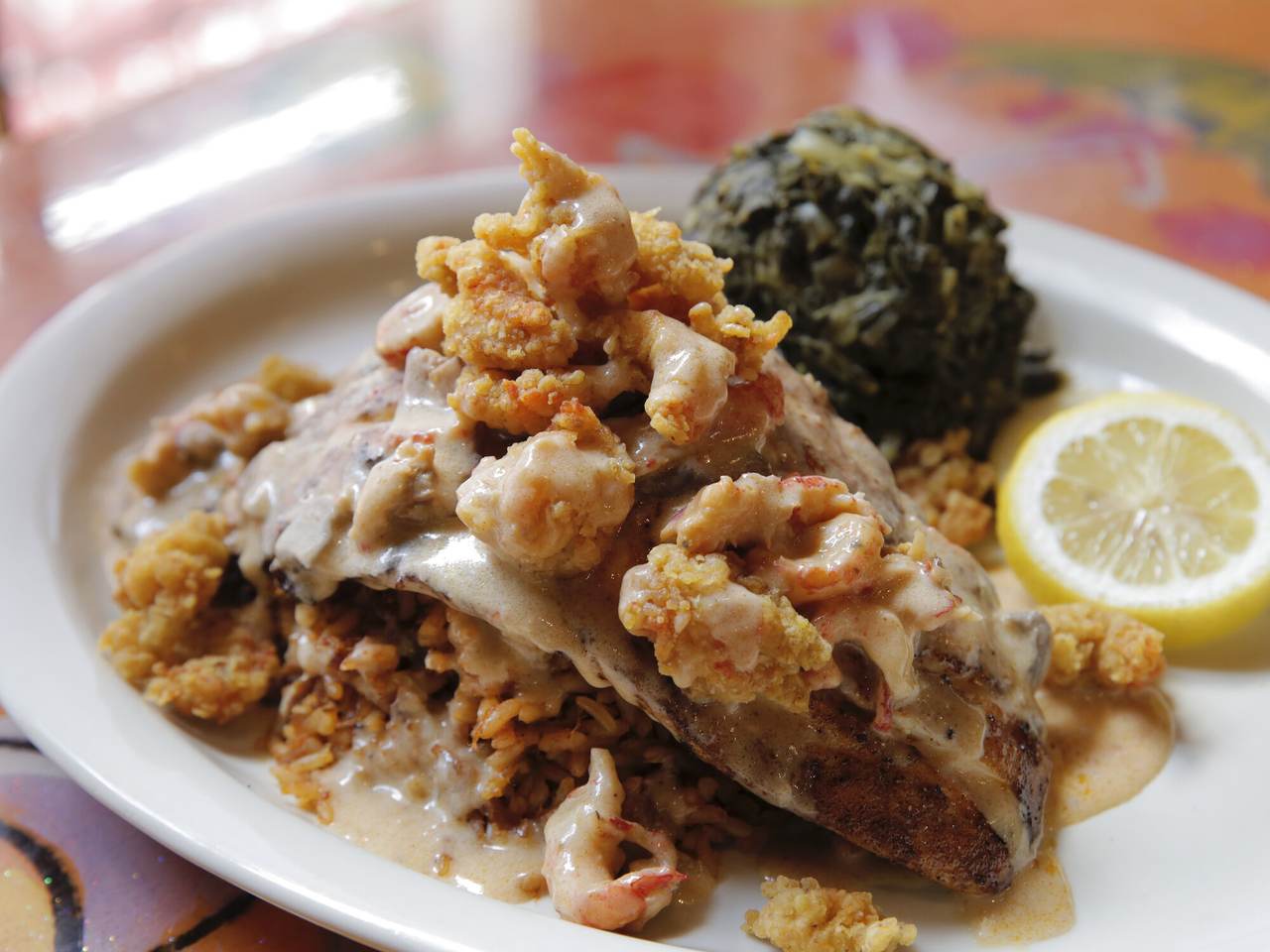 Blackened redfish LaFourche topped with crawfish mushroom cream sauce and fried crawfish tails, with mustard greens and lemon