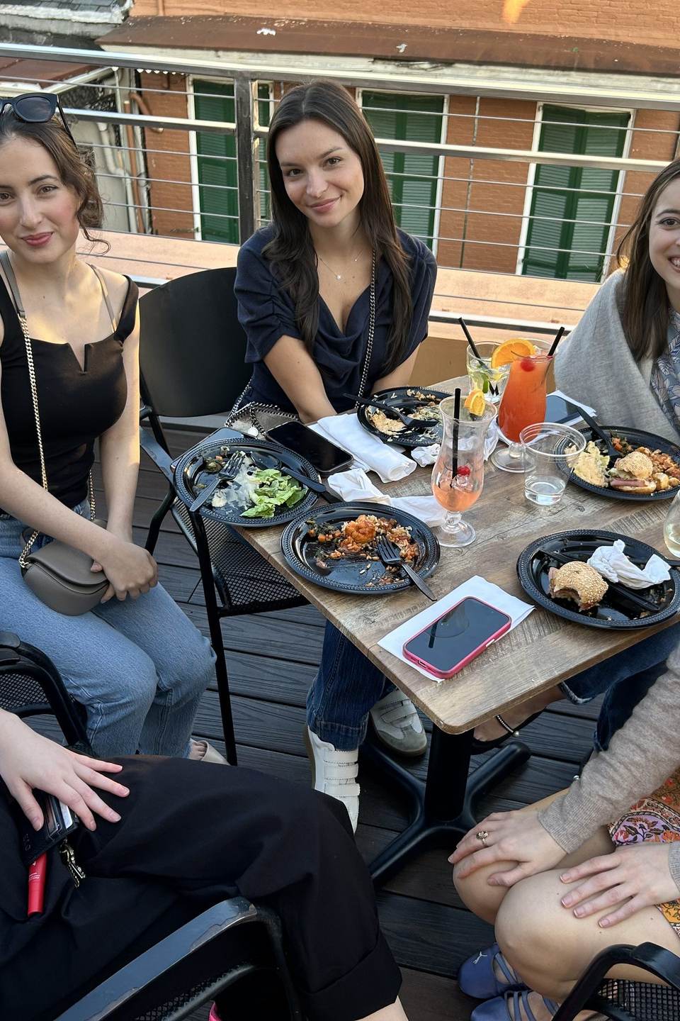 Young friends smiling over lunch and cocktails at a table on Mambo's rooftop
