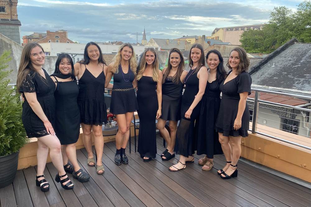 Eight friends posing together on Mambo's rooftop deck with the French Quarter skyline behind them