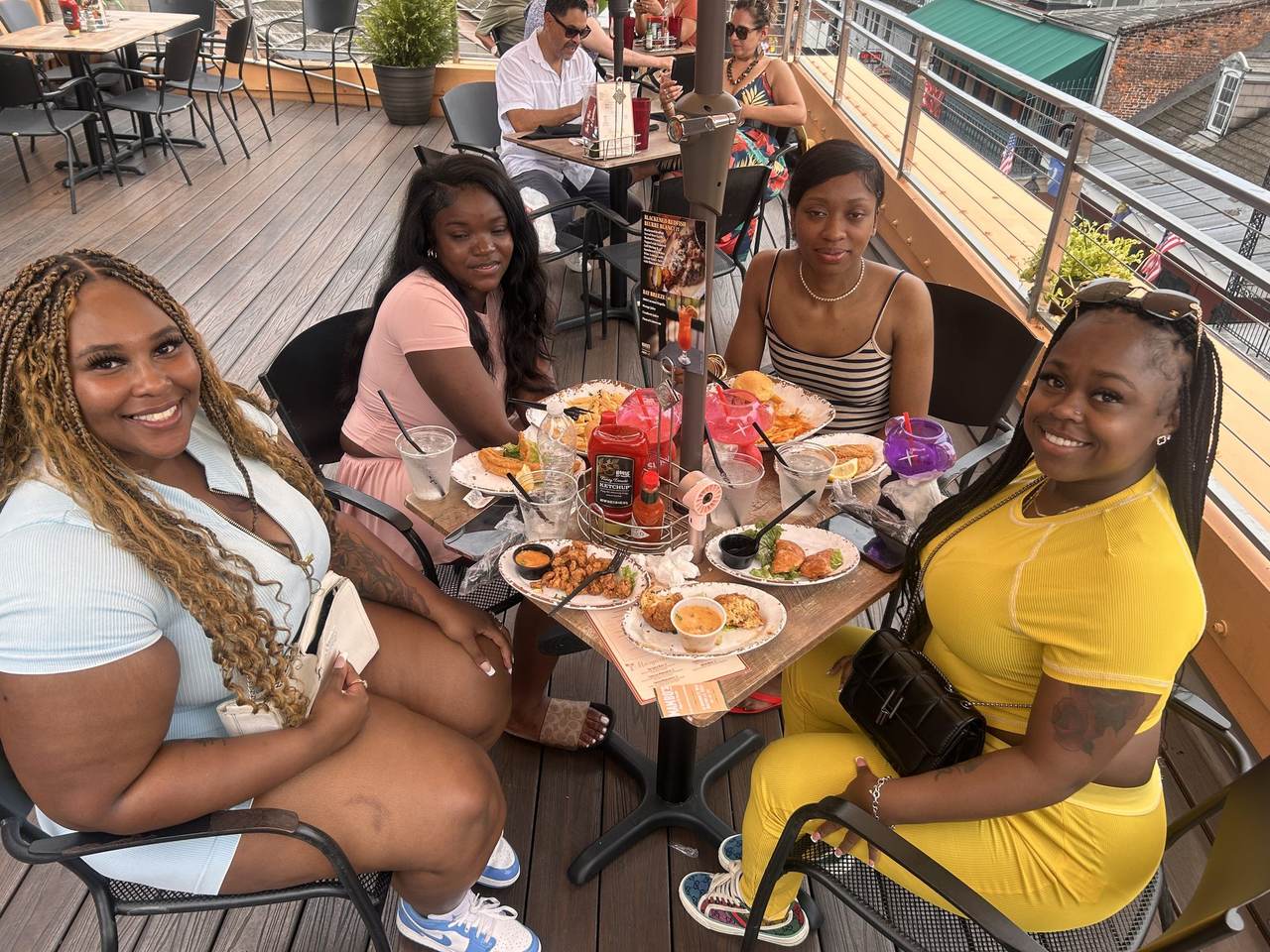 Friends sharing plates and cocktails around a table on Mambo's rooftop